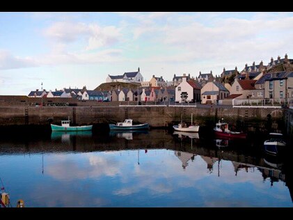 Quaint European bay with boats and small town in the background.