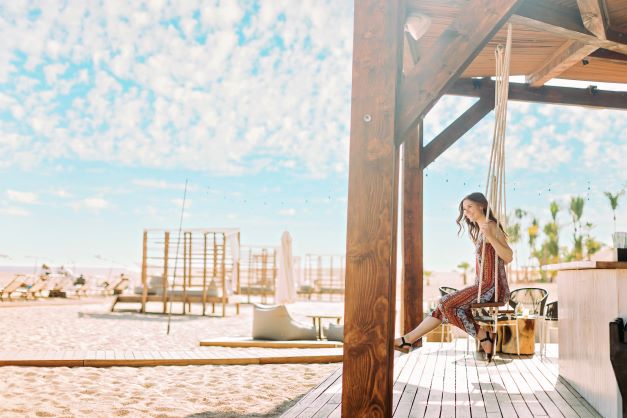 Beachside cabana swing, smiling woman, Los Cabos, Mexico. 